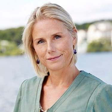 Lisa Rejler standing in front of water with cliffs behind, in a light green shirt