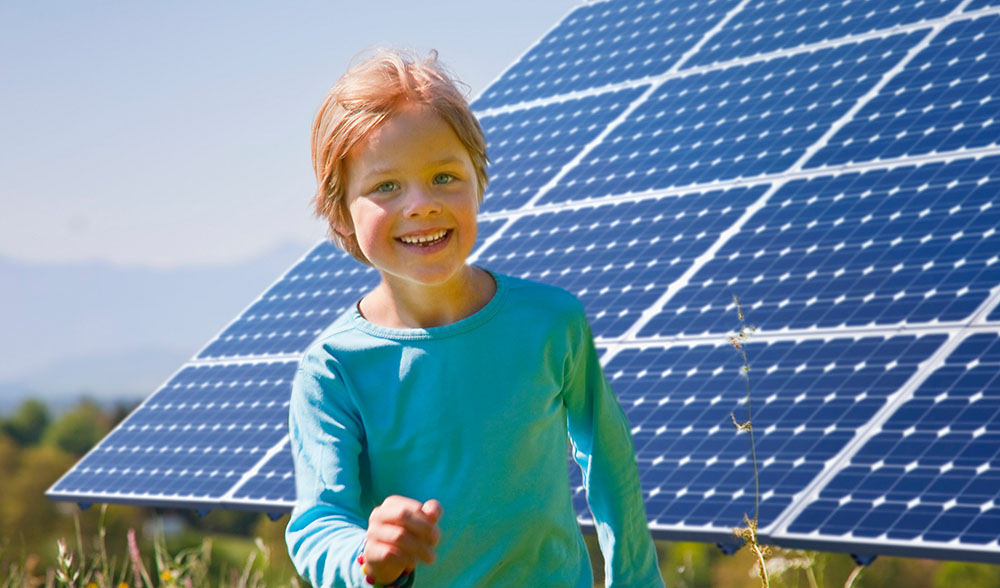 Boy playing in field by solar panel